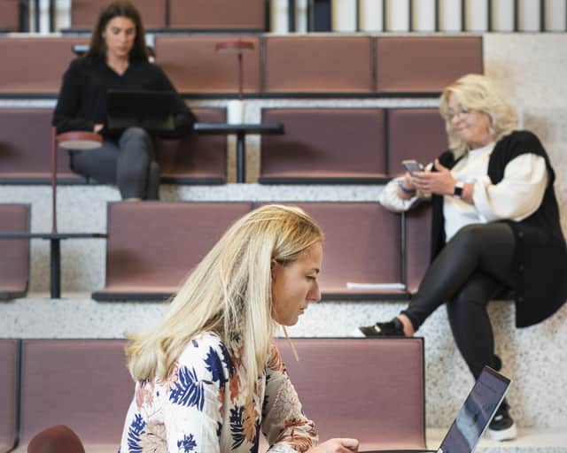Three people sitting in an auditorium.